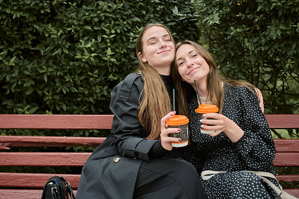 istock Young girlfriends enjoying coffee and gossip on park bench 2254151876