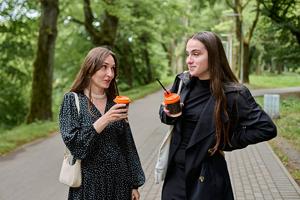 istock Young girlfriends gossiping over coffee during stroll in green park 2254151930