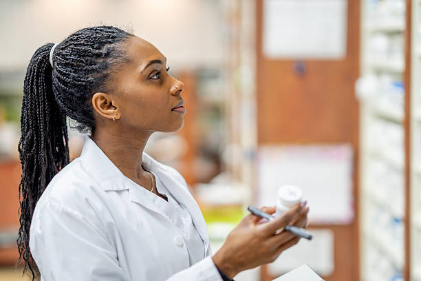 istock Black Female Scientist in Lab Coat Analyzing Tablets and Prescriptions in a Pharmacy Setting 2254153881