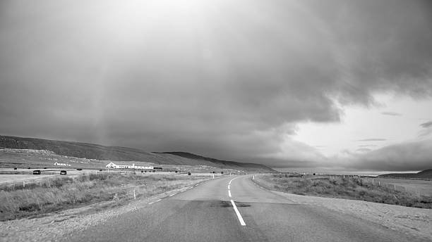 Scenic empty road stretching across Iceland under vibrant sunset sky and mountains.