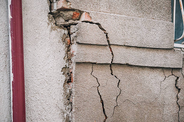 istock Building exterior showing significant structural damage with deep cracks in the concrete facade, exposing underlying brickwork. Signs of decay 2254171794