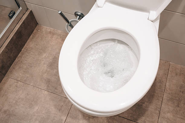 istock White ceramic toilet flushing clear water with visible bubbles, ensuring hygiene in a contemporary tiled bathroom setting 2254171859