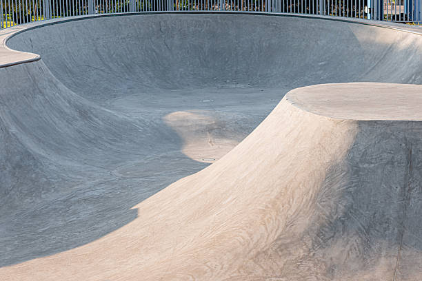 istock Empty concrete skate park featuring various ramps, bowls, and curves, illuminated by late afternoon sunlight creating deep shadows 2254171864