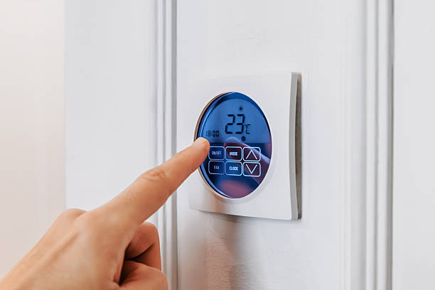 istock Hand adjusting a modern smart thermostat displaying temperature and settings, managing indoor climate and energy efficiency 2254171874