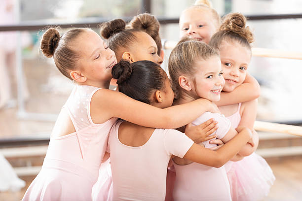 istock Young ballet dancers share a joyful group hug in a light-filled studio. 2254174392