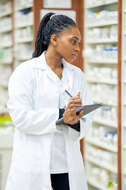 istock African American Pharmacist in White Lab Coat Writing on Clipboard in Pharmacy Setting 2254176179