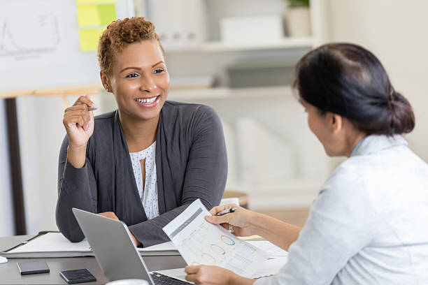 istock Two women engaged in a professional discussion, collaborating over documents and a laptop. 2254179966