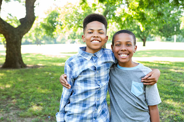 istock Two young brothers share a joyful moment outdoors in a park. 2254181677