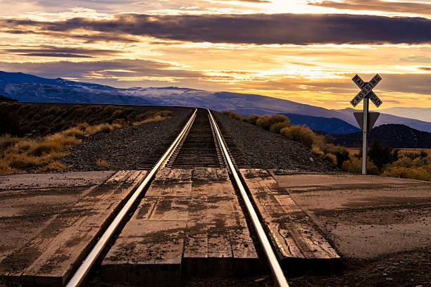 Scenic view with train tracks leading off into the distance with high mountains in background.