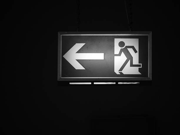 black and white image of an electrified exit sign glowing and shining in darkness