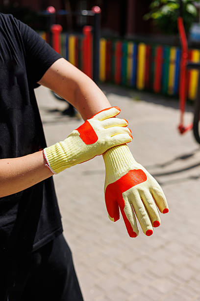 istock A hardworking individual is preparing for outdoor tasks by putting on protective gloves, enjoying the warm sunlight of a clear day for safety and efficiency in their upcoming work 2254195300