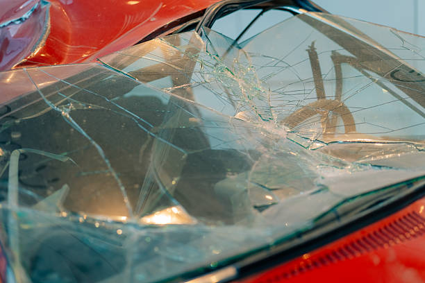Close-up of a cracked windshield on an old, rusted vehicle. Visible steering wheel and dashboard through damaged glass.