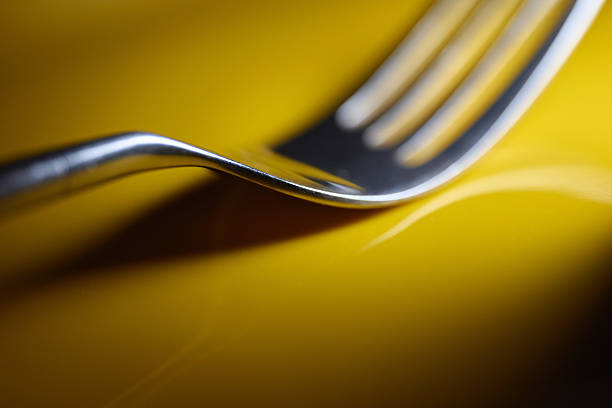 Macro Detail of Silver Fork Tines on Yellow Background. High quality photo