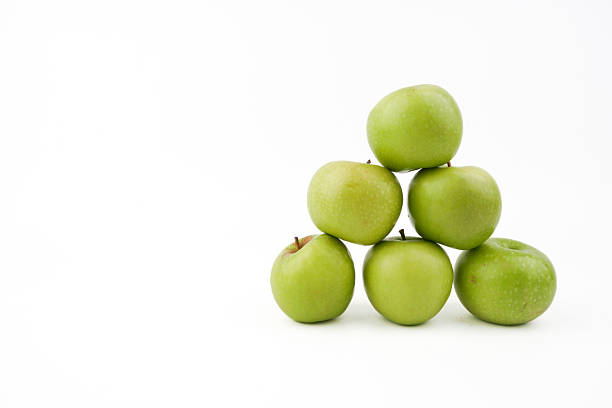 Stacked green apples isolated on white background representing fresh fruit display, healthy eating, natural produce, and simple food arrangement in clean minimal presentation.