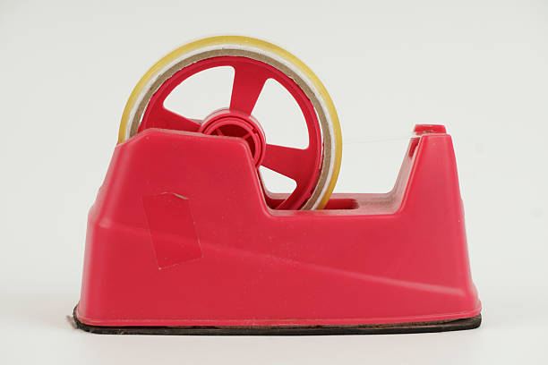 Red tape dispenser on white background representing office supply, packaging tool, stationery equipment, and everyday workplace accessory in simple minimal presentation.