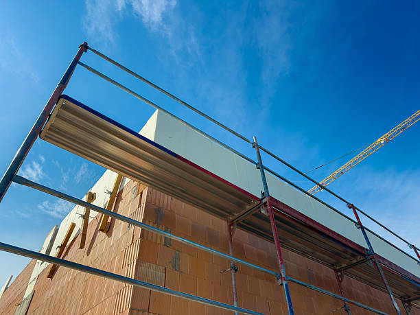istock Vibrant construction site under a clear blue sky with scaffolding and a crane in action near a city landscape 2254200318