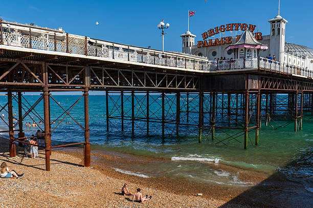 Brighton and Hove, UK - 20th June 2025The Brighton Palace Pier with its classic white Victorian pavilions on a sunny summer day. People are walking along the deck, while others are enjoying the weather on the beach and into the sea.