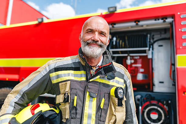 istock Confident Mature Firefighter Smiling Beside Bright Red Fire Truck in Daylight 2254202512