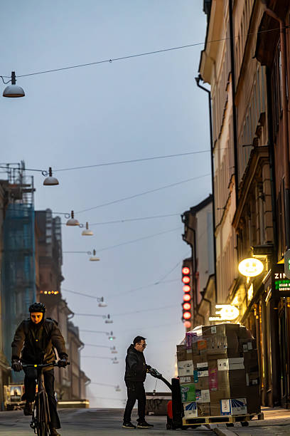 Stockholm, Sweden Oct 29, 2025 A bicyclist rides in the early morning on Gotgatan in the Sodermalm district and a merchandise delivery on a palett.