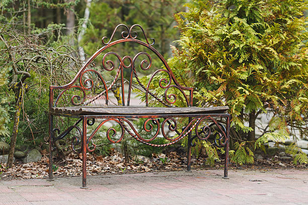 A beautifully designed iron bench sits in a peaceful garden, framed by vibrant greenery. The scene captures the essence of a calm spring day, perfect for relaxation.