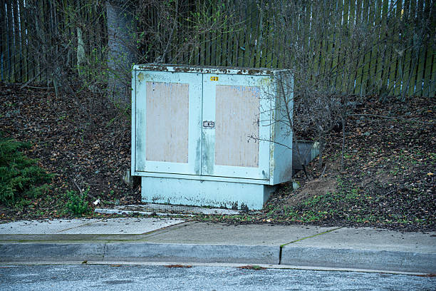 istock Weathered utility box with plywood panels on doors sits beside a sidewalk 2254213935