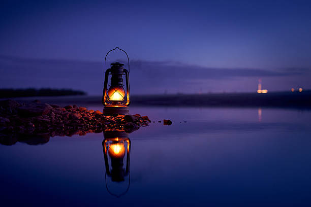 istock Burning old lantern on rocks reflecting in the river 2254213968