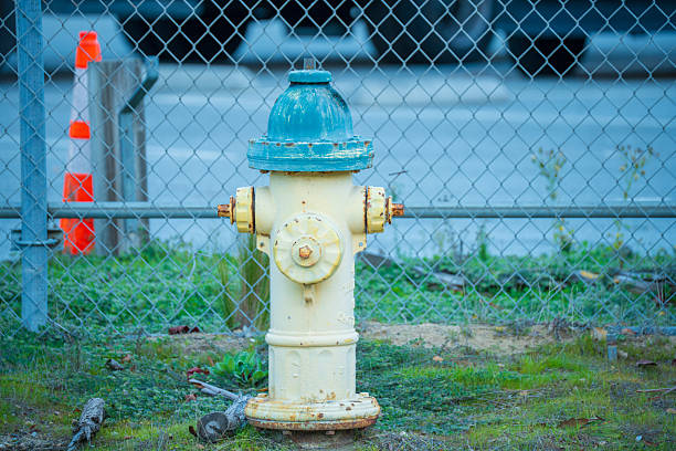 istock A weathered yellow and blue fire hydrant stands behind a chain-link fence 2254213983