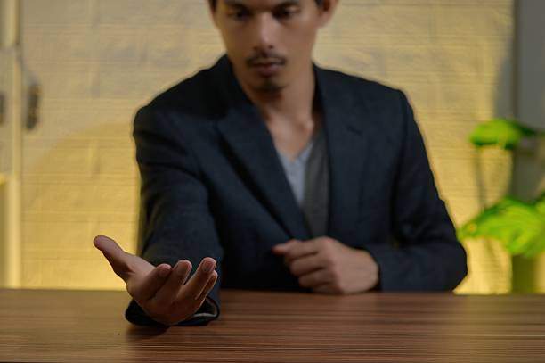 A confident man in a suit extends his hand in a welcoming gesture, inviting assistance or engagement. The warm background adds depth to the scene, ideal for business themes.