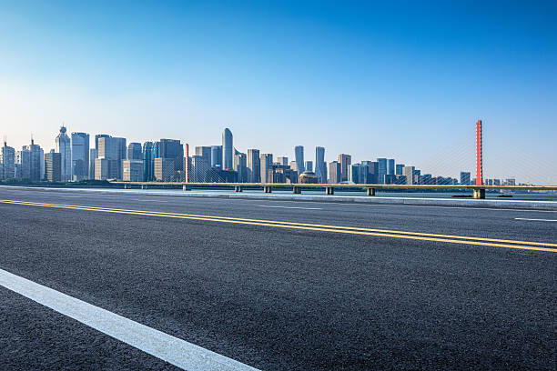 istock Empty asphalt road and modern city skyline with bridge under clear blue sky. 2254221140