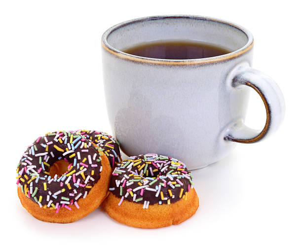 Grey ceramic cup of black tea served with three mini chocolate glazed donuts with colorful sprinkles. Sweet breakfast or snack isolated on white background.