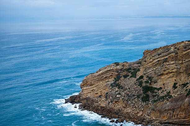 Cabo Espichel Sesimbra Portugal December 25 2025. Rocky cliffs and layered coastline overlook the blue Atlantic Ocean.