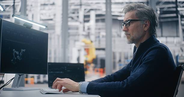 istock Senior Engineer Typing Dual Screen Workstation, Monitoring 3D Robotic Model on Screen 2254232526