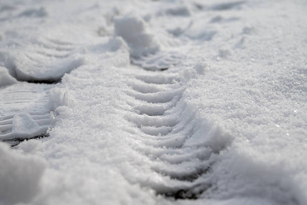 Shoe tracks and footprints are visible in fresh snow, illustrating winter weather conditions, pedestrian movement and potential safety risks on cold, slippery surfaces.
