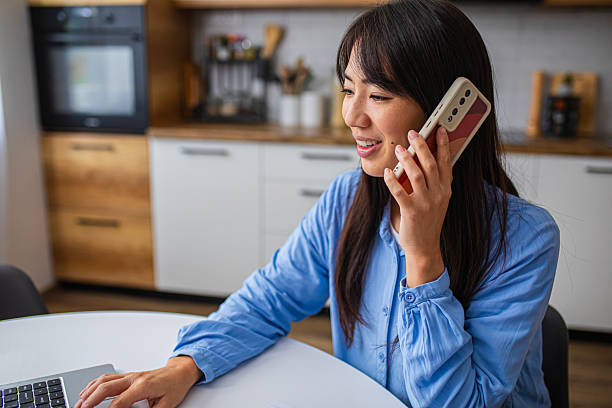 istock Smiling Woman Working from Home While Talking on Phone 2254239319