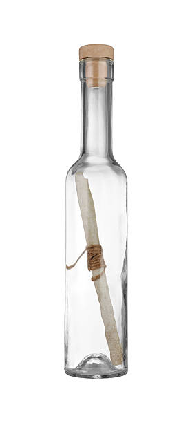 Against a background of sand lies a bottle containing a message saying \
