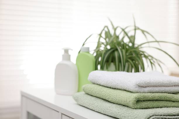 Stack of fresh terry towels on white table in bathroom, closeup. Space for text