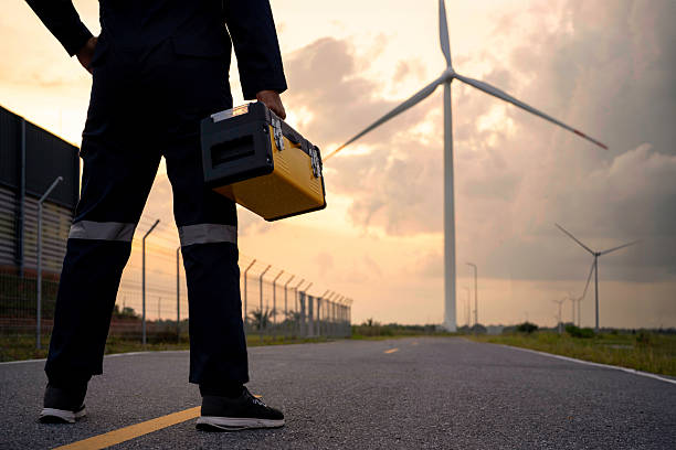 Renewable energy maintenance. Engineer wearing uniform inspection and survey work in wind turbine farms rotation to generate electricity energy. Maintenance engineer working in wind turbine farm.