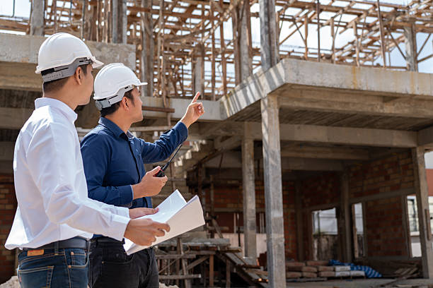 istock Engineer group and worker meeting, discussion with construction blueprint on site work and point finger to the site workplace. Builders and architects in hardhats with blueprint on construction site 2254246343