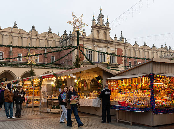 Krakow, Poland – December 3, 2025: Wooden stalls decorated with lights and garlands line the main square during the Christmas market, as visitors browse gifts and seasonal products in the historic city center.