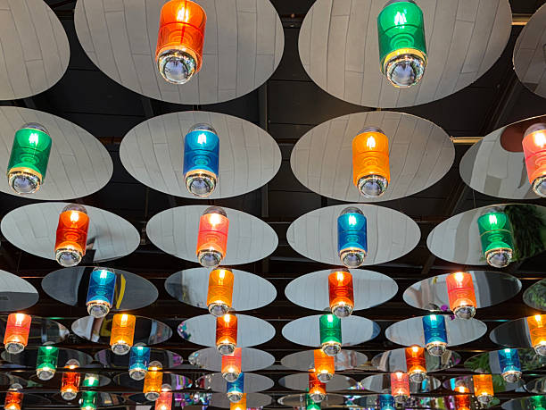 Stock photo showing rows of illuminated, cylindrical, metal, multicoloured lanterns mounted to a ceiling.