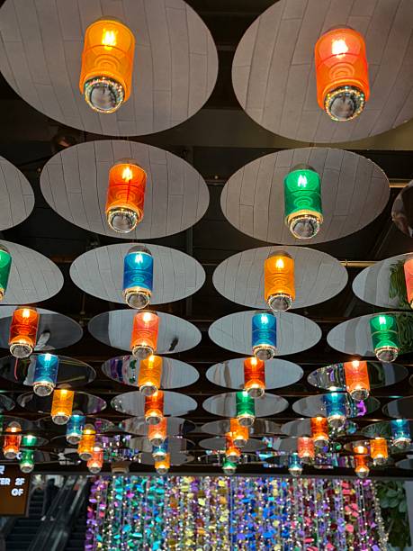 Stock photo showing rows of illuminated, cylindrical, metal, multicoloured lanterns mounted to a ceiling.