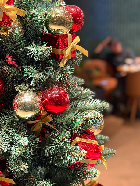 istock Image of festive artificial christmas tree with realistic fake needles, decorated with red baubles and ornaments, surrounded by wrapped presents and gifts 2254252843
