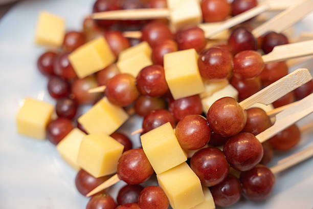 Cheese and Grape Skewers. Cheese cubes and red grapes arranged on wooden skewers. A simple and elegant snack for wine tastings or party buffets.