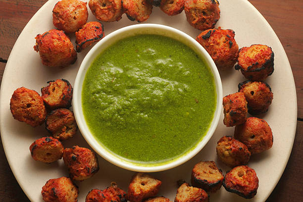 crispy tandoori soya chunks served on a white plate with fresh green chutney on a rustic wooden table. Healthy vegetarian Indian snack and protein-rich appetizer.