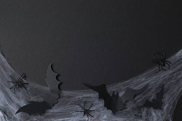 istock Halloween holiday decorations including cobweb, bats and spider on black background, top view 2254256226