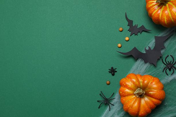 istock Halloween holiday decorations including pumpkins, spiders, bats on green background 2254256297