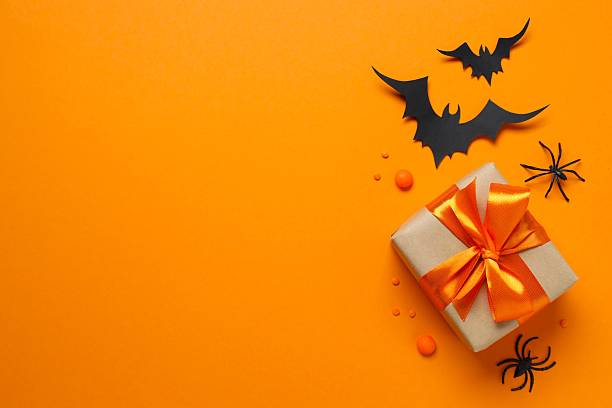 istock Halloween holiday decorations including gift box, pumpkins, spiders, bats on orange  background 2254256476