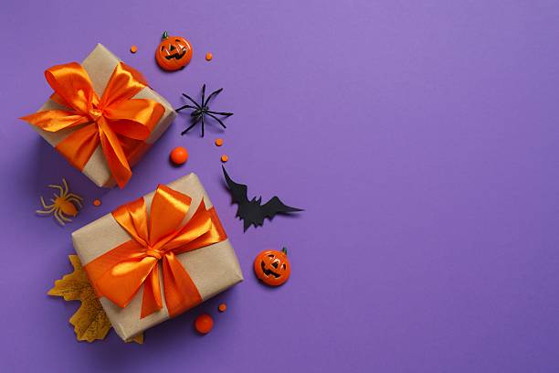 istock Halloween holiday decorations including gift boxes, pumpkins, spiders, bats on purple background 2254256531