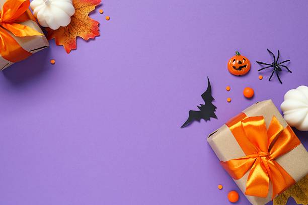 istock Halloween holiday decorations including gift boxes, pumpkins, spiders, bats on purple background 2254256561