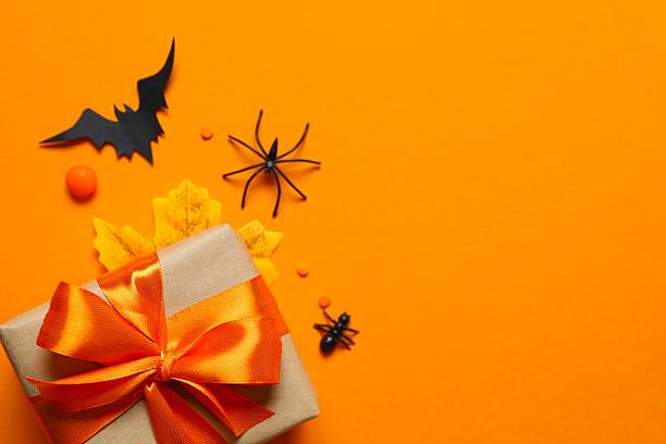 istock Halloween holiday decorations including gift box, pumpkins, spiders, bats on orange  background 2254256620